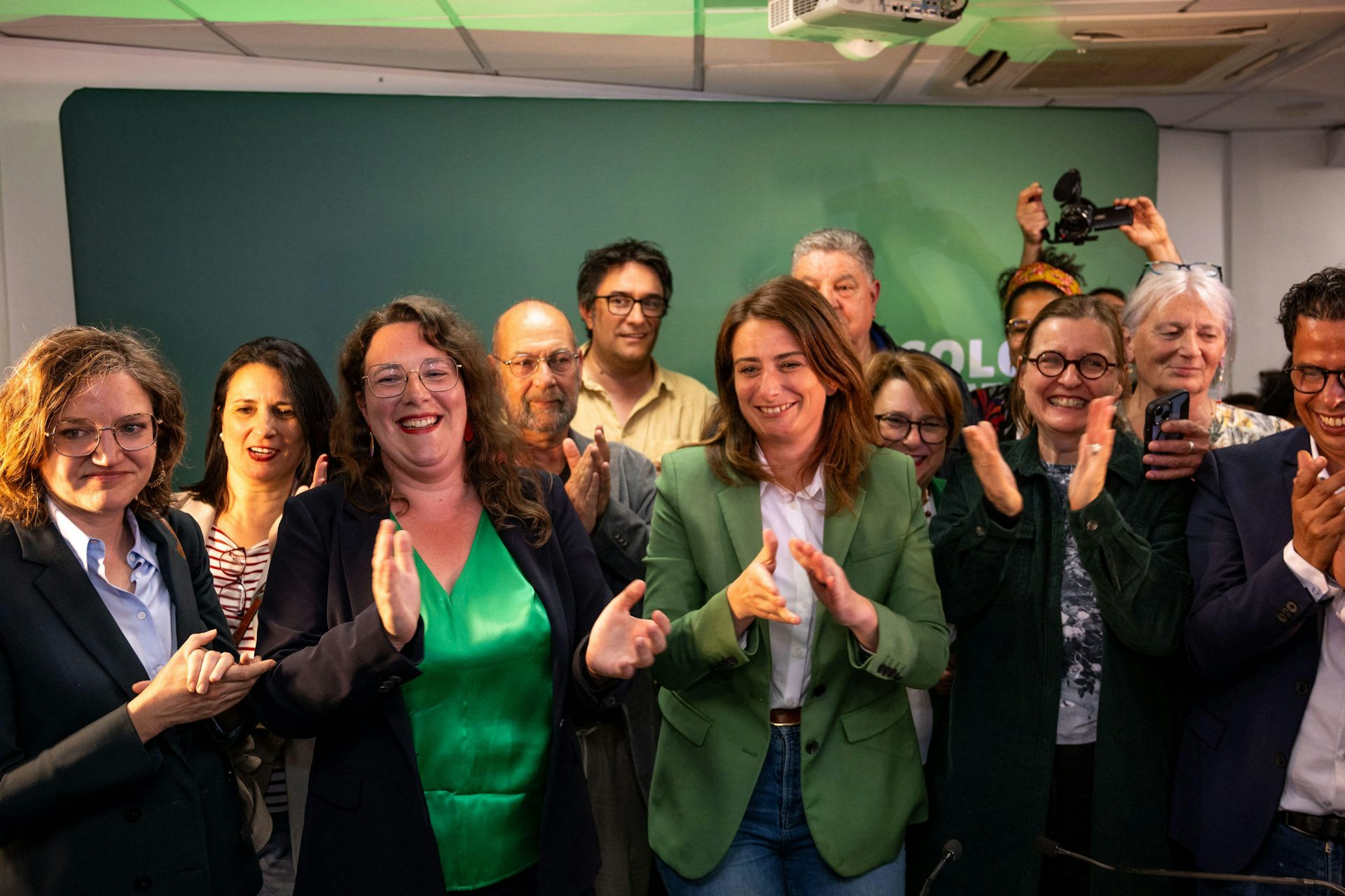 Green party members smiling and clapping.