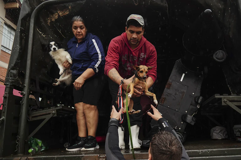 People and their pets evacuate a flooded area after heavy rain in Sao Sebastiao do Cai, Rio Grande do Sul state