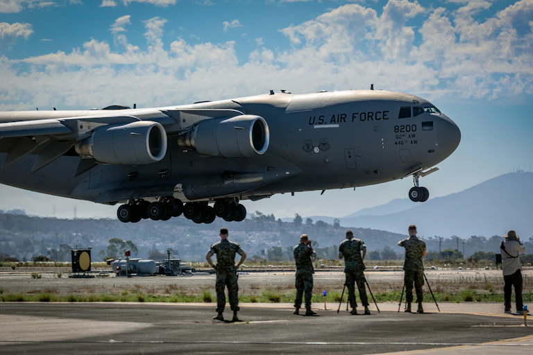 US air force boeing plane coming in to land as personnel watch on the runway