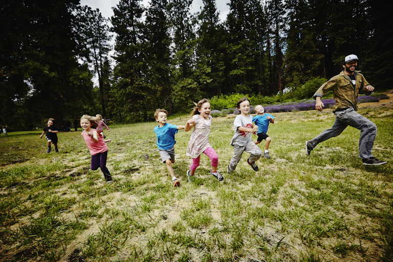 children and teacher running in field