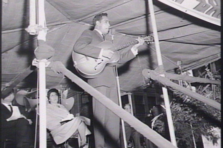 Little with a guitar on stage.