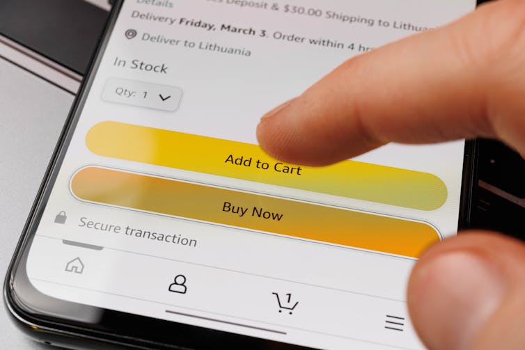 finger hovers above 'buy now' button on an online store seen on a phone screen
