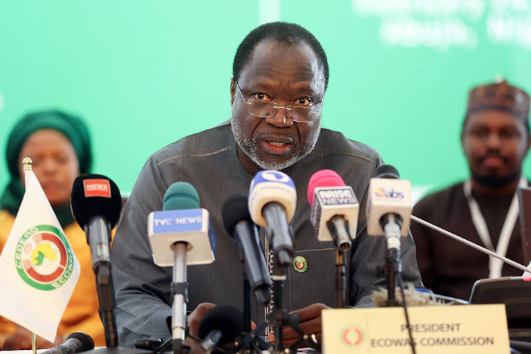 A man speaking into a pack of microphones
