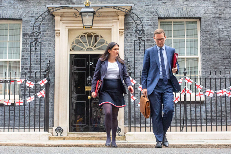 Two people crossing road away from 10 Downing Street