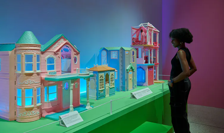 A woman looks at several plastic Dreamhouses