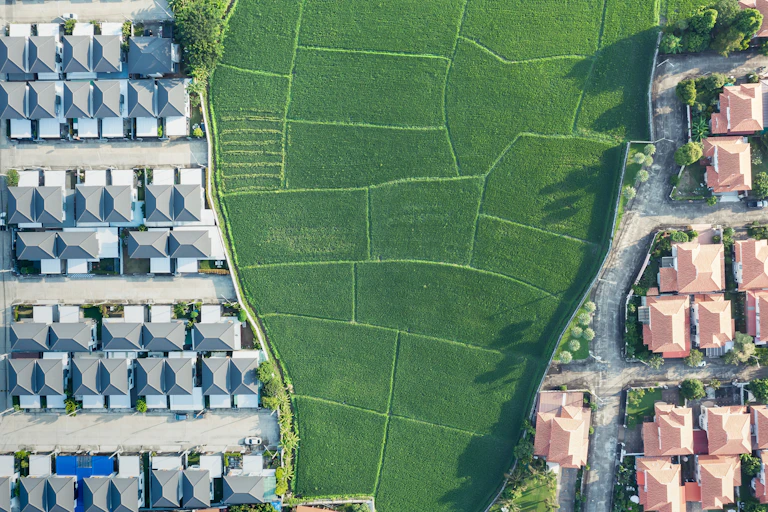 aerial shot of roofs of houses with green fields in centre of pic