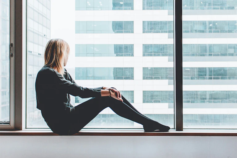 A woman sits looking out a window.