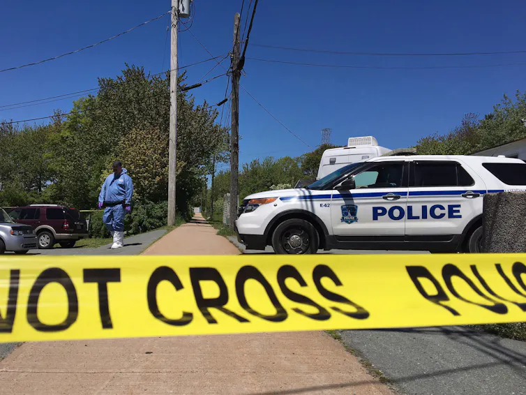 Yellow police tape in front of a police cruiser.