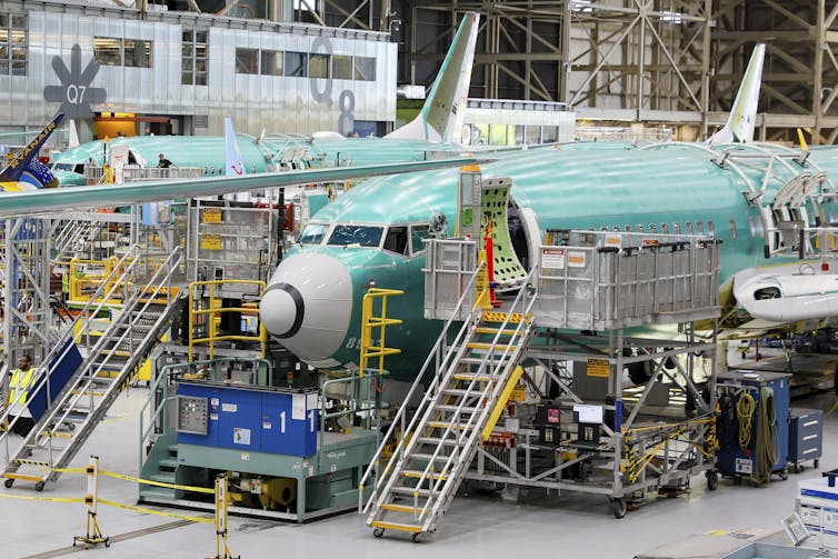 Aviones en el interior de una fábrica. Unas escaleras conducen a la puerta delantera abierta de cada avión.