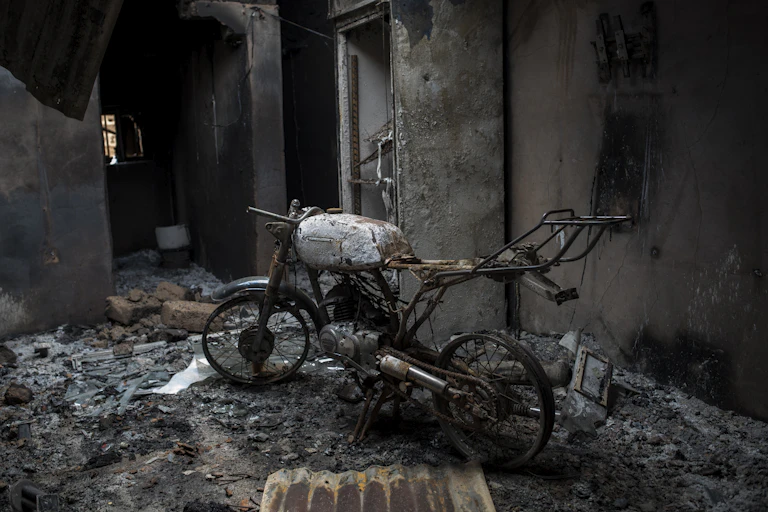 A burnt motorcycle in a burnt building