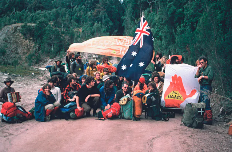 A group of people with an Australian flag and a sign that says no dams in a forest.