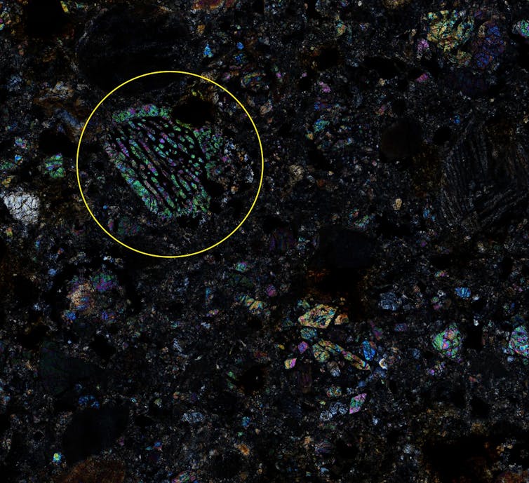 Close-up of a multicoloured mineral surface on a dark background.