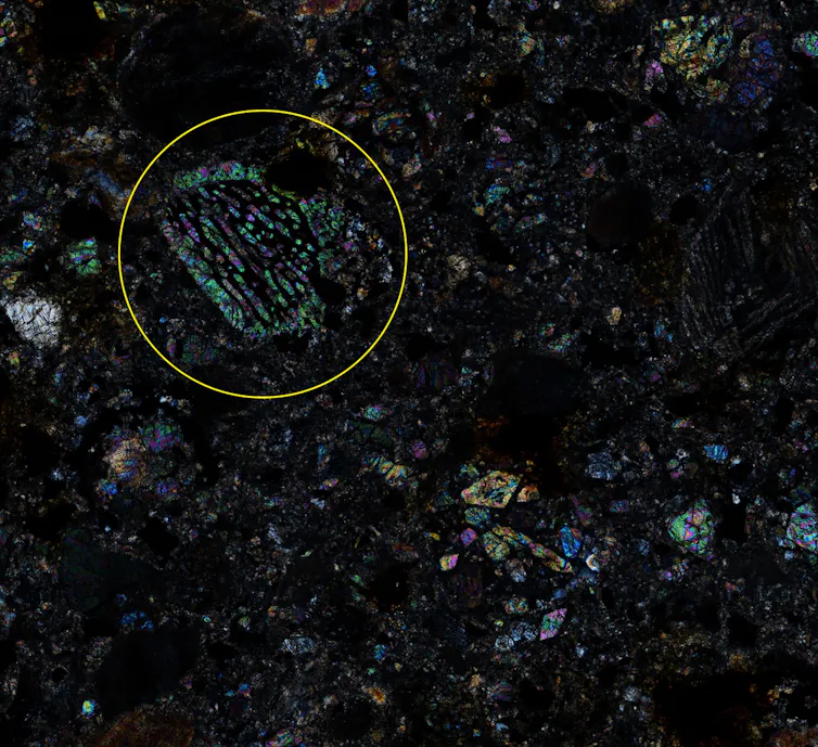 Close-up of a multicoloured mineral surface on a dark background.