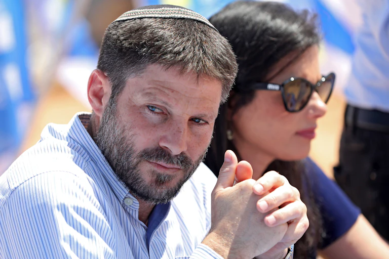 Bezalel Smotrich sat with his hands clasped together and looking to the side.
