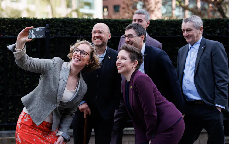 Politicians in suits gather for a selfie.