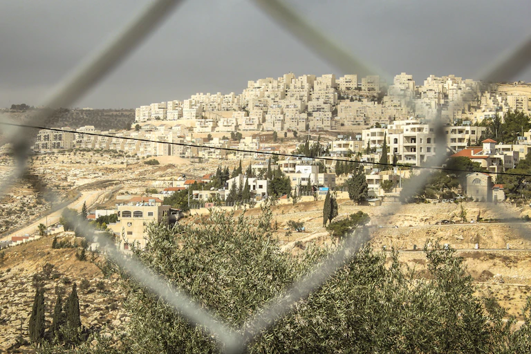 A photo of an Israeli settlement in the West Bank taken through a fence.