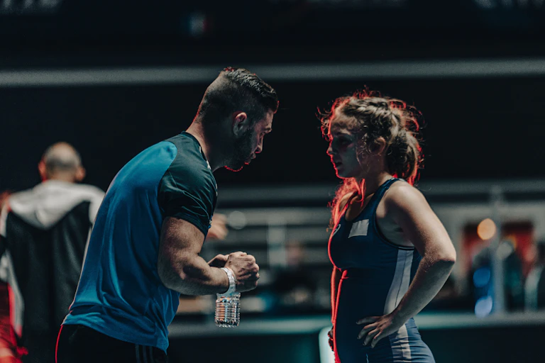 Un entraîneur coache une lutteuse pendant un match.