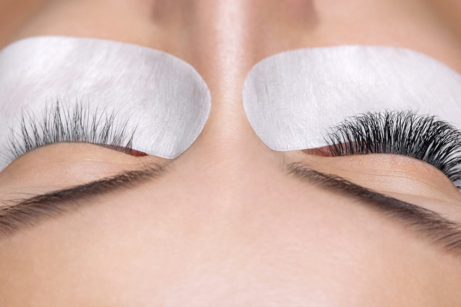 Close-up of closed eyes with protective gel pads and professionally applied eyelash extensions