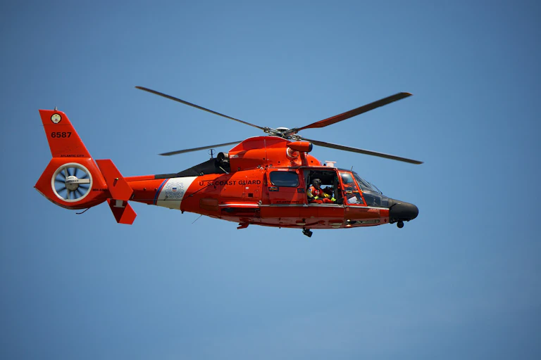 a red helicopter with a black nose and white stripe in flight