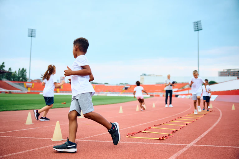 Des enfants font des exercices physiques dans un stade pour évaluer leur condition physique.