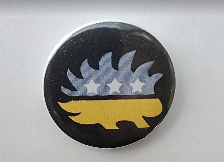 A black button with a stylized porcupine on it.