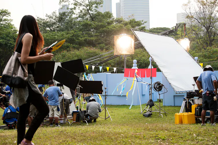 A woman stands at a film set surveying what is happening.