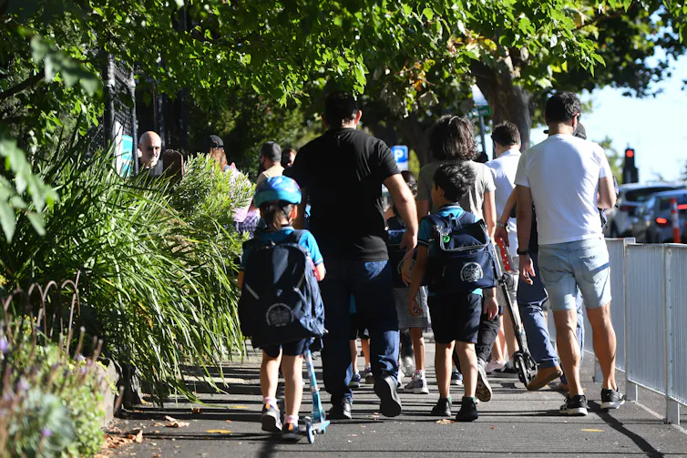Parents and children walk along the footpath. One child is on a scooter.