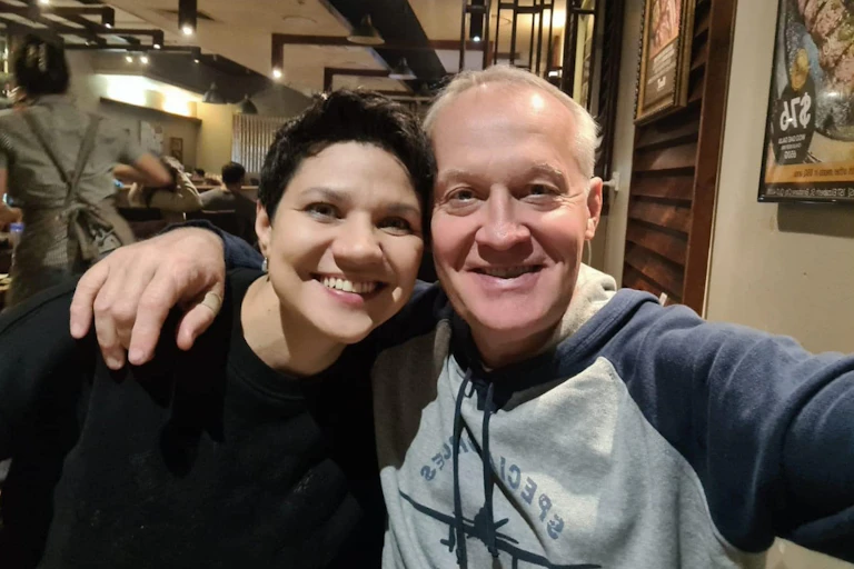 A man and a woman smile in a selfie in a restaurant