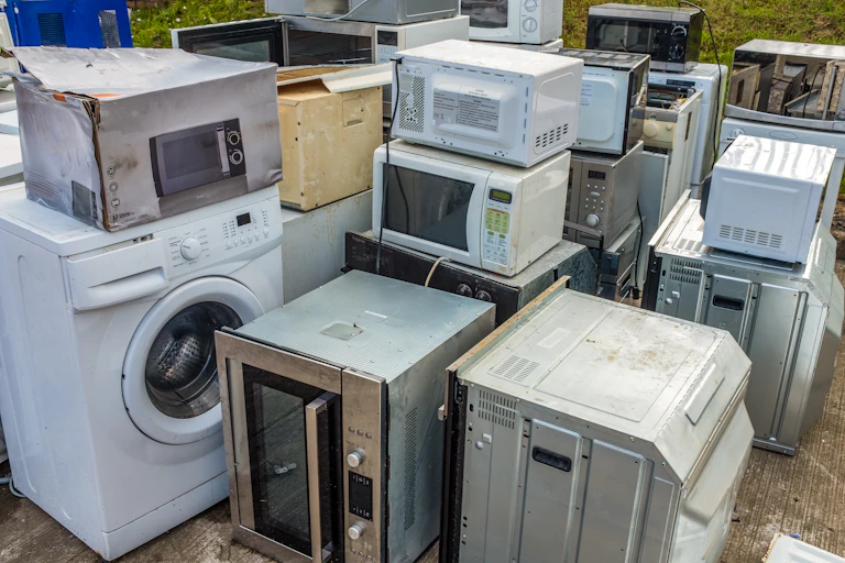 A collection of old, broken domestic applicances (Ovens, microwaves and washing machines)