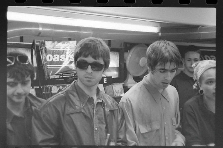 black and white photo of Oasis at a record signing ahead of the release of Definitely Maybe.