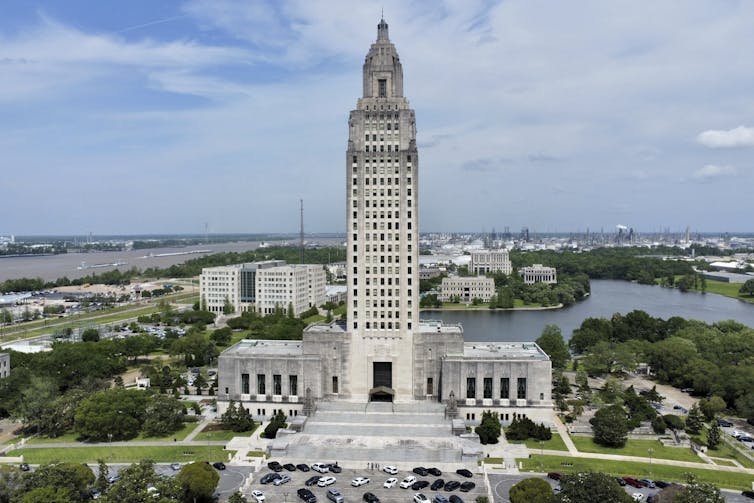 A white state capitol building with its tall tower is prominent against a small-town background.
