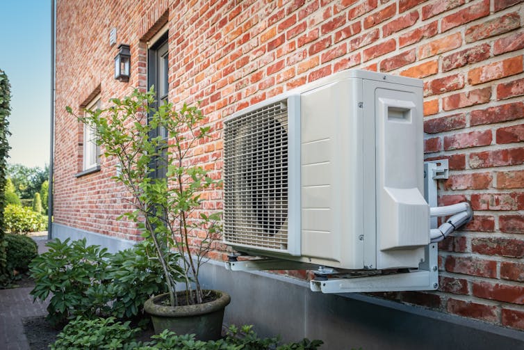An air-source heat pump on the side of a house.