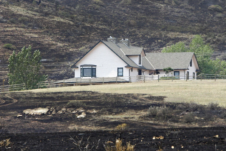 A house is surrounded by burned grass as a result of the High Park wildfire near Bellvue, Colo., in June 2012. The wildfire has burned over 180 homes.