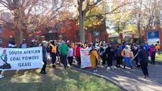 Protestors outside the Petmin coal mine office holding up a banner that says South African coal powers Israel
