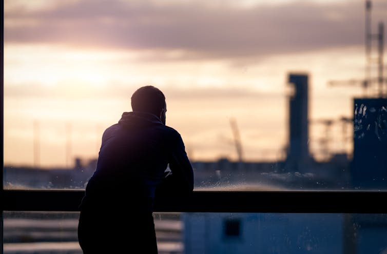 A man looking out over a balcony.