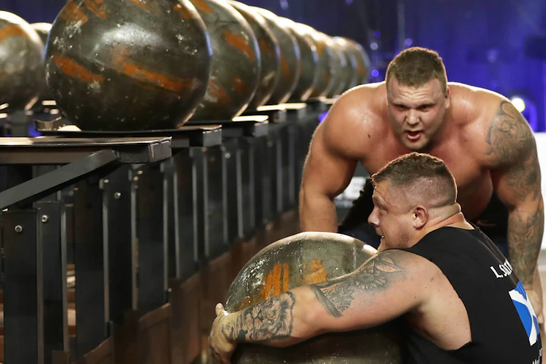 Competitors attempt to lift a huge stone during a strongman event