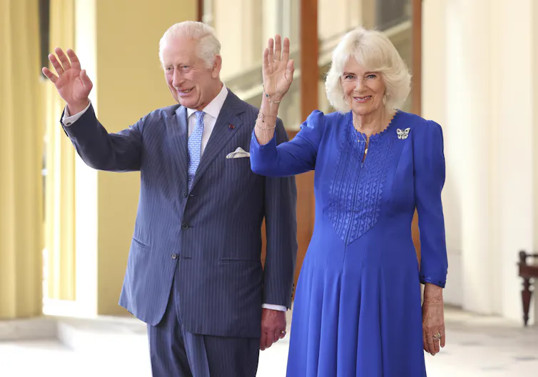 The king and queen wave in a photo.
