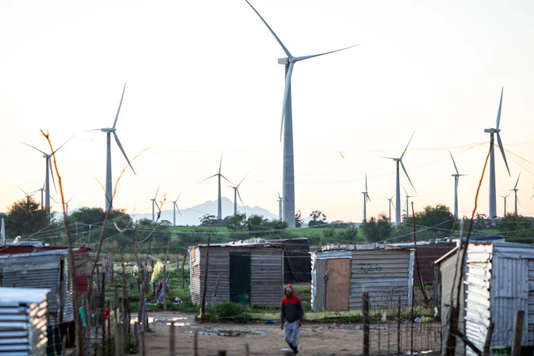 Wind turbines in the background, informal shacks in the foreground