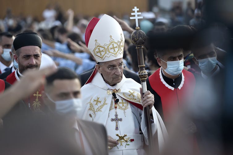 A Christian leader dressed in a white robe holding a staff.