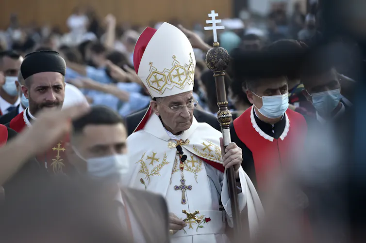 A Christian leader dressed in a white robe holding a staff.