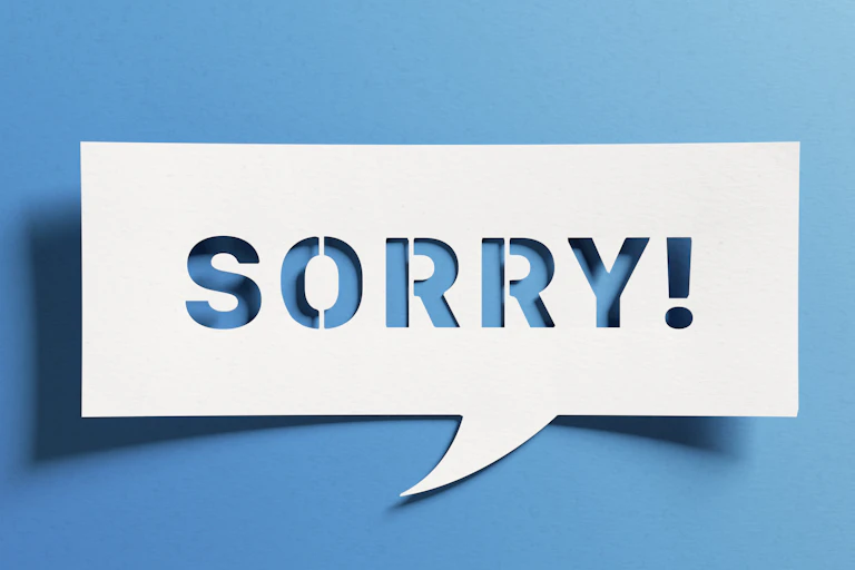 Paper speech bubble cut out to make the shape of the word 'sorry!'