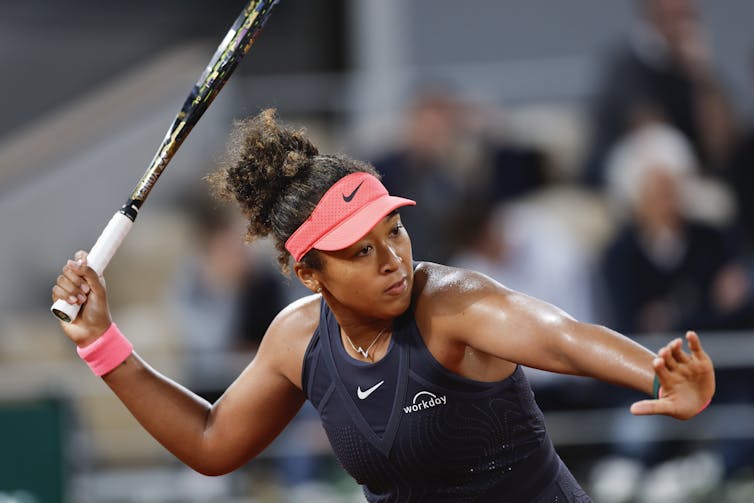 A woman in a tennis outfit raises a racket to take a shot.