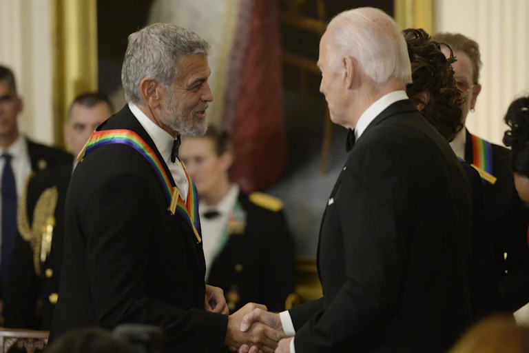Joe Biden and George Clooney shaking hands at a reception.