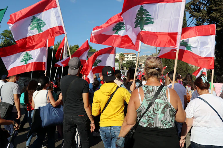 Christians in Lebanon marching down a street holding Lebanese flags.
