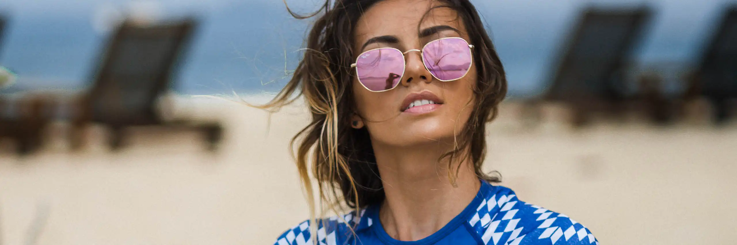 Une femme sur la plage se protège du soleil avec un vêtement conçu à cet effet et des lunettes de soleil.
