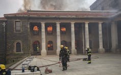 The UCT building on fire with a firefighter in the foreground
