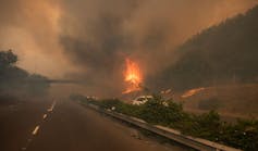 A fire blazes across a busy road in Cape Town with smog filling the air