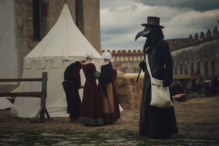 A recreation of a plague scene with a mask-wearing plague doctor in the foreground