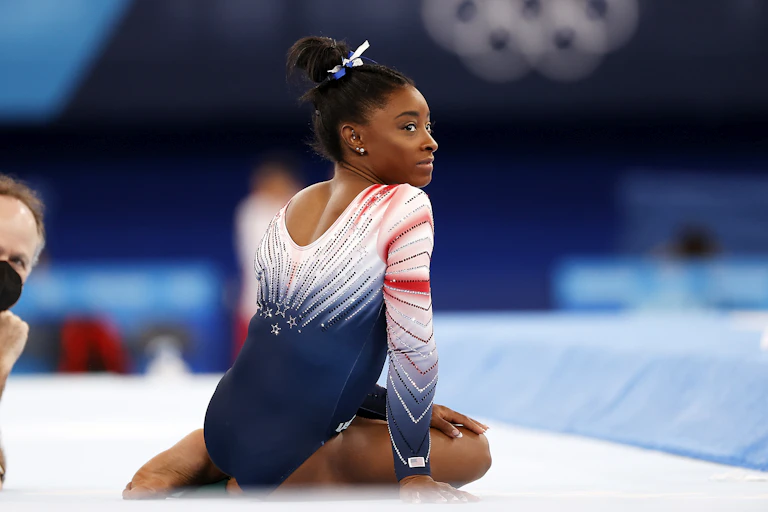 Simone Biles sitting on the floor at the Olympics
