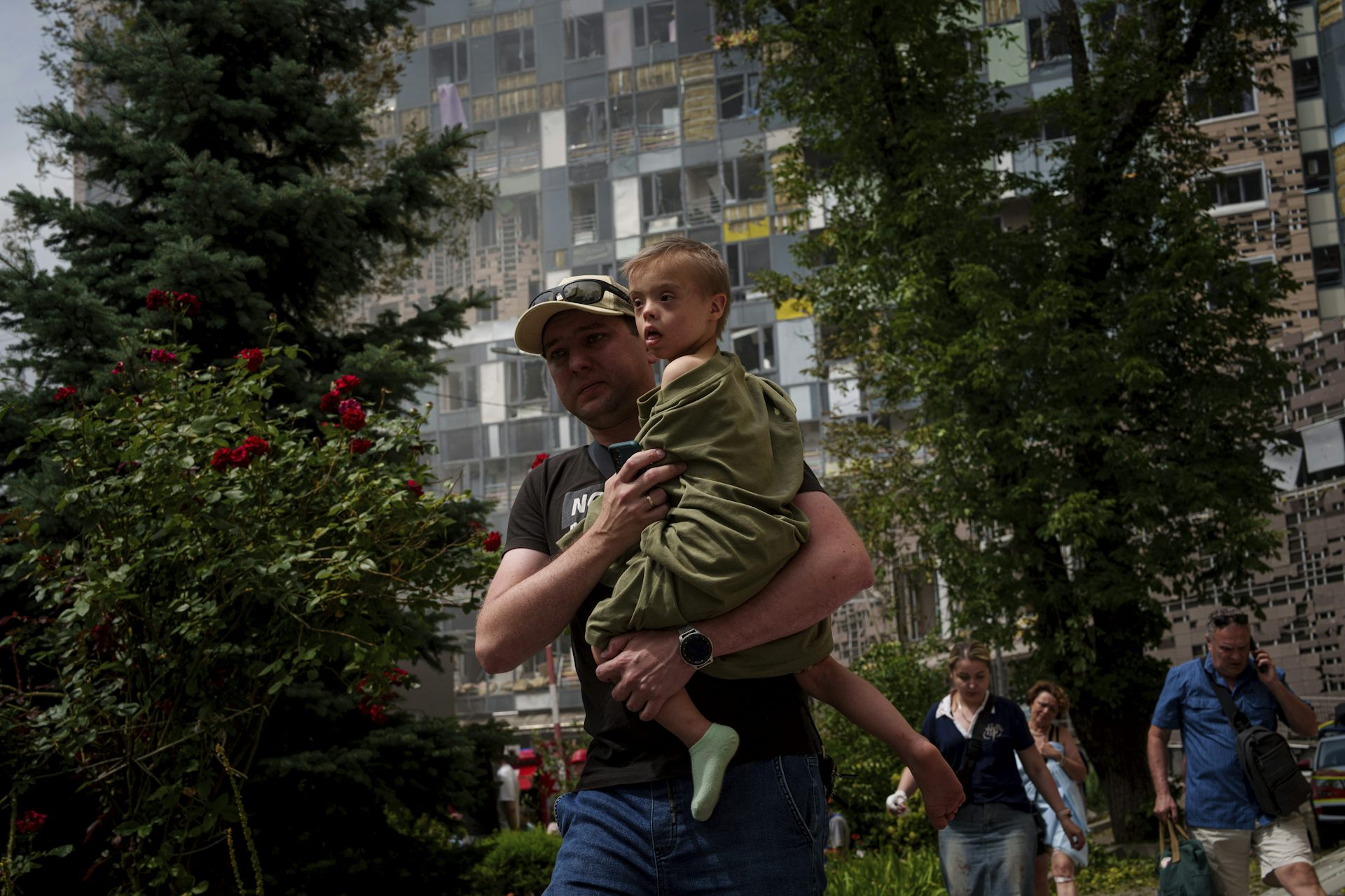 A man in a ball cap holds a boy.